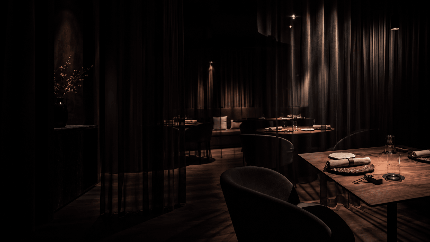 Dunkler, ruhiger Restaurantraum mit eingedecktem Tisch im warmen Licht.